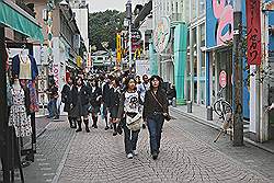 Harajuku - jongeren; extreem gekleed volgens Japanse begrippen, met daarachter meisjes in schooluniform