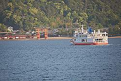 Miyajima - de boot terug, met een veerboot en de torii van de Itsukushima tempel in de verte