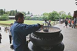Nara - onderhoud aan de wierookpot; uitgebrande wierookstaafjes worden verwijderd en nieuwe brandstof wordt in het midden geplaatst